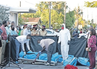 The bodies of the shooting victims are removed from the scene on Thursday night. (Photo courtesy Tribune newspaper)