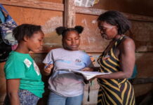 CMCFeature-Displaced by violence, a Haitian girl finds hope at school. Young Haitian girl smiling in school uniform, holding books