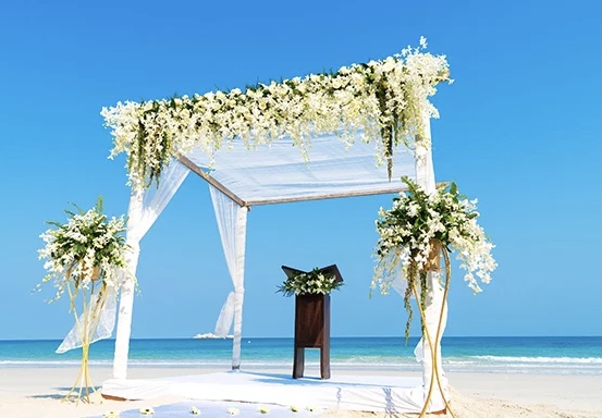 Barbados Named Caribbean’s Leading Wedding Destination A couple exchanging vows on a tropical beach in Barbados at sunset, surrounded by turquoise waters and palm trees.