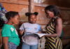 CMCFeature-Displaced by violence, a Haitian girl finds hope at school. Young Haitian girl smiling in school uniform, holding books