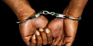 JAMAICA–Police charge a man recently deported from The Bahamas. Jamaican man in handcuffs escorted by police officers at station after being charged following recent deportation from The Bahamas as part of 85-inmate group