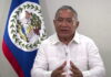 BELIZE-Government announces new measures to deal with the impact of rising oil prices. Belize government official at podium announcing energy measures with oil price chart