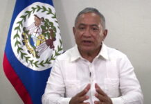 BELIZE-Government announces new measures to deal with the impact of rising oil prices. Belize government official at podium announcing energy measures with oil price chart