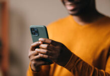 GUYANA–Mobile subscriptions in Guyana surpass one million. Person using smartphone in Guyana with network signal bars and million-subscription graphic