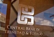 TRINIDAD-Central Bank to intervene following commercial bank increase in fees. Central Bank governor speaking at podium with fee chart on screen
