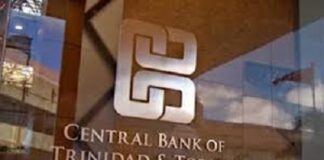TRINIDAD-Central Bank to intervene following commercial bank increase in fees. Central Bank governor speaking at podium with fee chart on screen